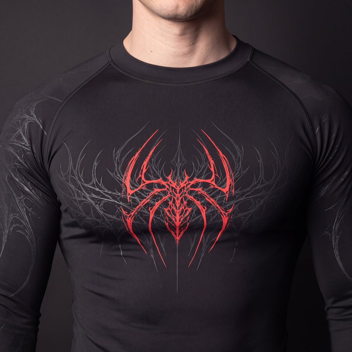 Close-up of the distressed red spider chest print and flatlock seams on the Symbiote Compression Shirt